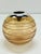 A contemporary yet elegantly restrained spherical vase of amber-tinted blown glass, distinguished by a series of precisely...