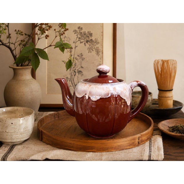 A beautifully sculptural vintage Japanese stoneware teapot featuring a rich chestnut-brown high-gloss glaze accented by a...