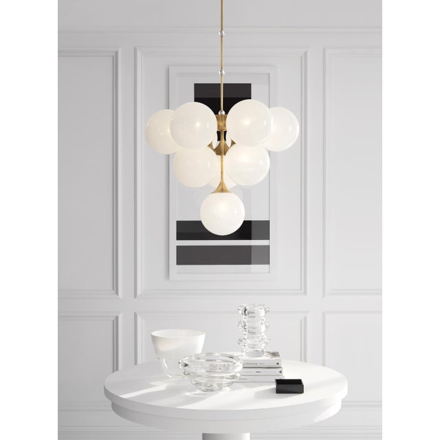 Cristol Tiered Chandelier in Hand-Rubbed Antique Brass with White Strie Glass Designer: AERIN Fixture Height: 23.25" Min....