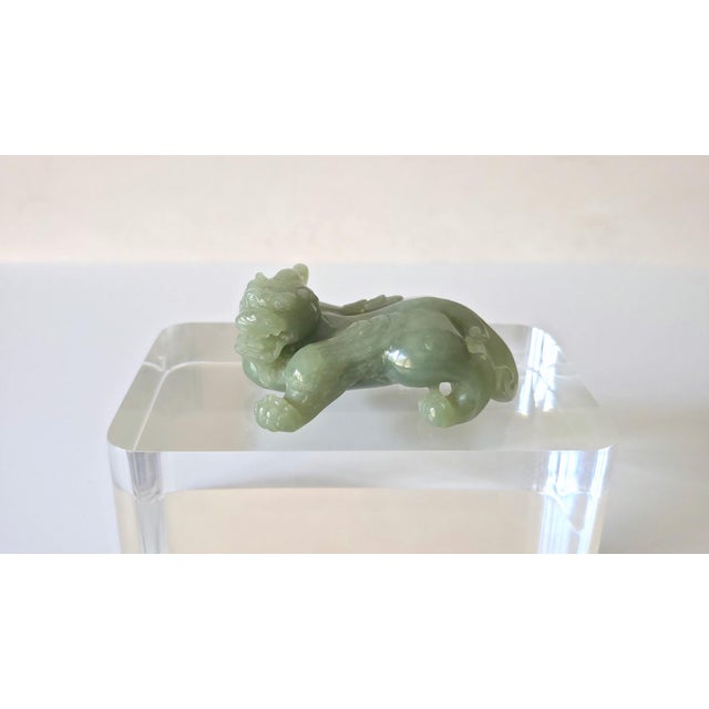A finely carved Chinese jade figure of a bixie, Qing Dynasty or Early Republic Period, circa 1850–1930. The grinning...