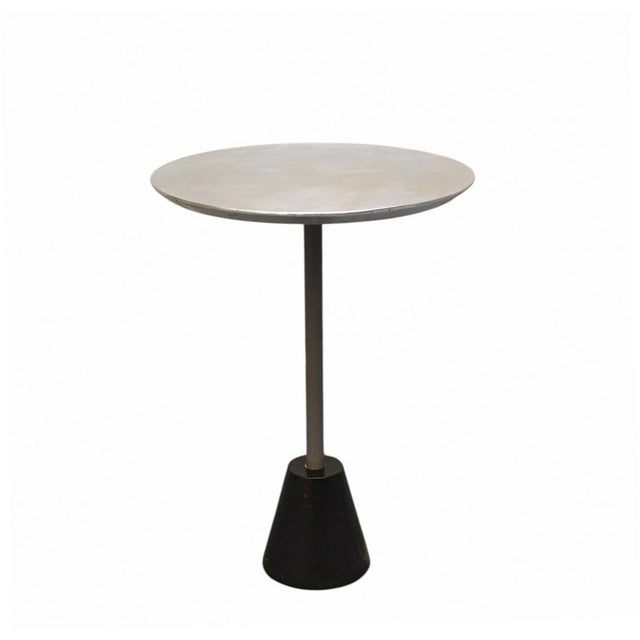 A tall coffee table with a round top, featuring a minimalist and sophisticated design. The structure combines contrasting...