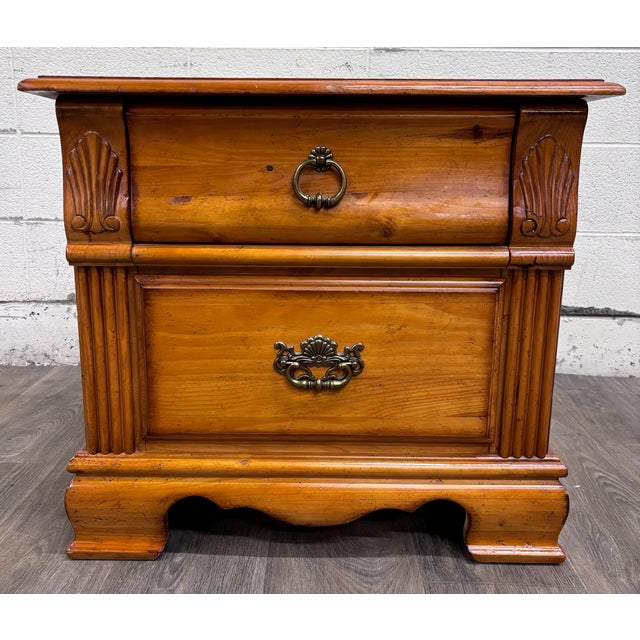 This is a Towood Lifee two-drawer nightstand in a warm light pine finish. Features carved shell accents, fluted...