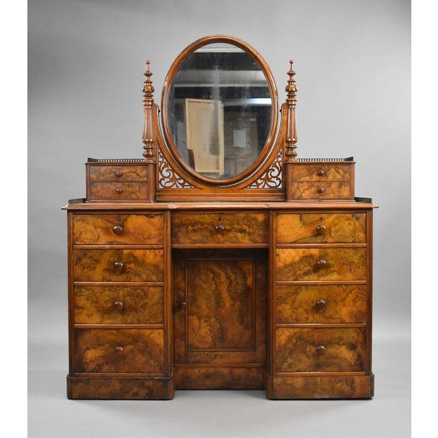 A fine quality burr walnut dressing table of elegant proportions, featuring a striking oval mirror flanked by decorative...