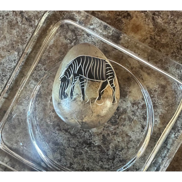 Unique hand-painted egg shaped stone featuring a detailed zebra design. The earthy tones of the stone complement the black...