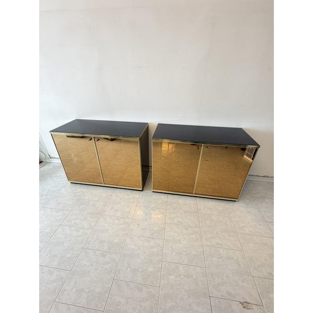 Set of two cabinets attributed to Renato Zevi, 1970, in gold mirrored glass and brass. Internal shelf. Black glass top....