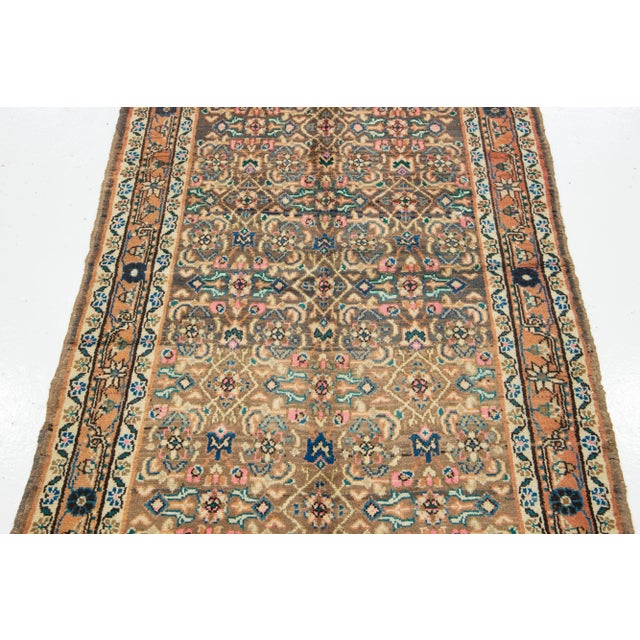 This Vintage Hamadan wool rug has an allover motif with accents in pink, orange, and blue with a light brown field. This...
