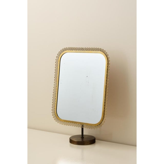 Table mirror in brass, possibly manufactured by Nordiska Kompaniet, 1950s. Brass, wave-shaped border decoration. Adjustable.