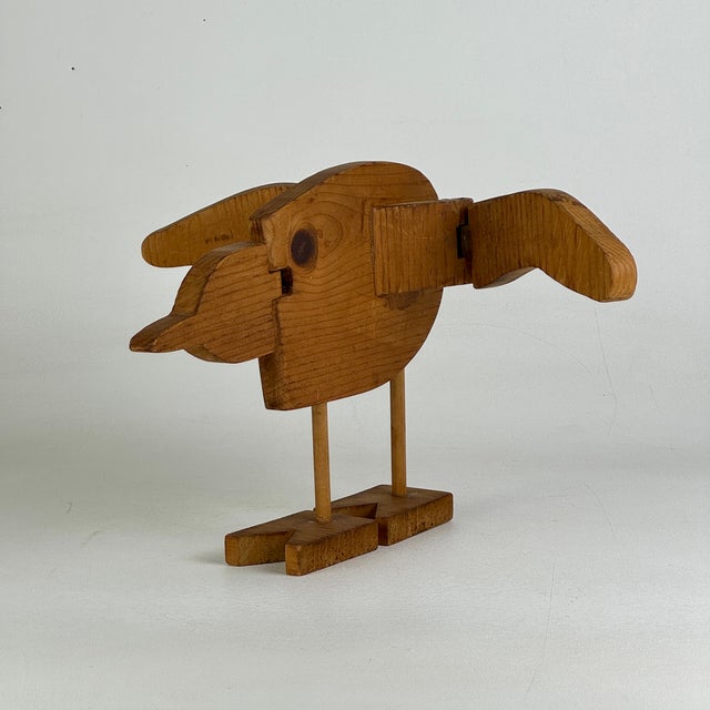 A delightful articulated Folk Art bird sculpture carved, cut, and assembled using light brown wood. The wings and the head...