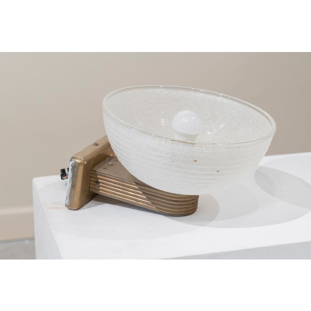 Pair of Art Deco torch-style wall sconces. They are secured to the wall by a brass arm and a thick, clear and white-...