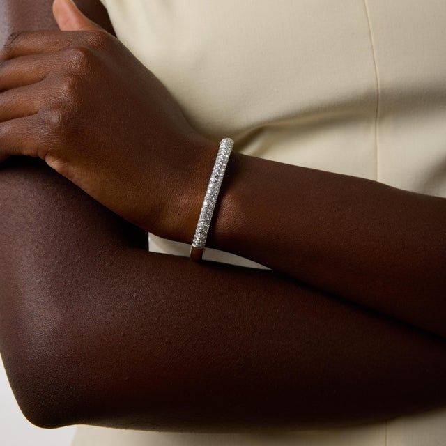 A striking example of vintage glamour, this elegant bangle bracelet from the 1970s showcases fifty-eight round brilliant...