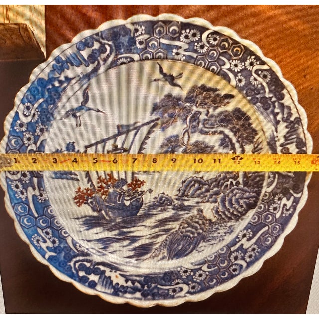 This vintage Japanese Imari ceramic plate showcases the classic blue and white color scheme, featuring a Takarabune...