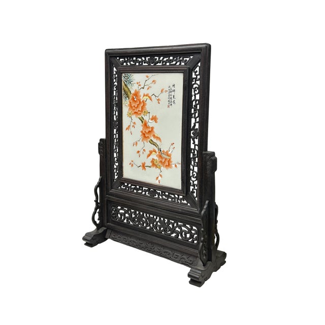 This elegant Chinese table screen features a central porcelain plaque delicately painted in the famille rose palette. The...