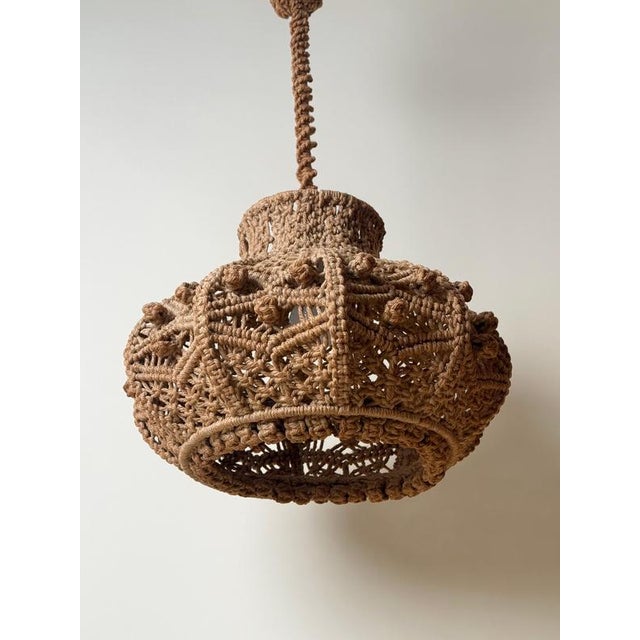 A beautiful 1970s hand-knotted macrame pendant lamp with a sculptural, rounded shade made from natural jute or hemp rope....