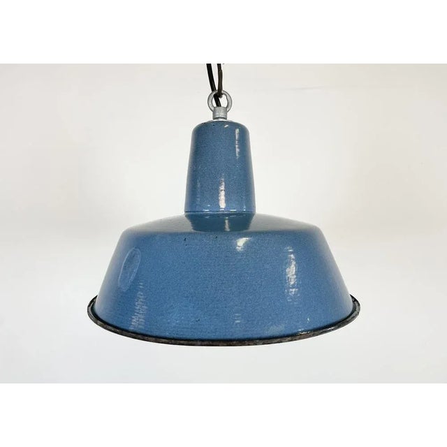 Industrial blue enamel pendant light made in Poland during the 1960s. White enamel inside the shade. Iron top. The...