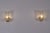 Pair of brutalist wall sconces, each consisting of a deeply engraved, gilded brass base supporting a thick, frosted glass...