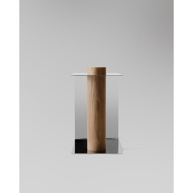 Table in polished stainless steel with a solid wood column. The Puru Side Table embodies the elegance of simplicity, using...