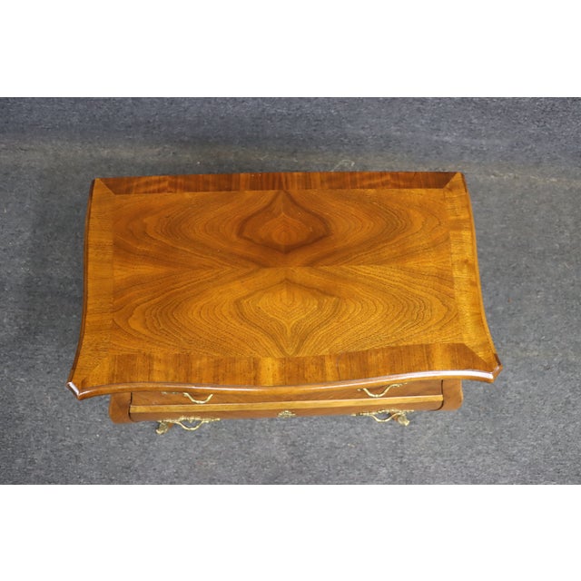 Elegant Baker French Bombay style nightstand with three drawers and a curved bombe form. Crafted in walnut and mahogany...