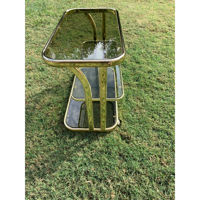 Absolutely stunning! 1970’s era Italian, bar cart. Brass plated with 3 tiers of smoked glass. It is on castors and rolls...