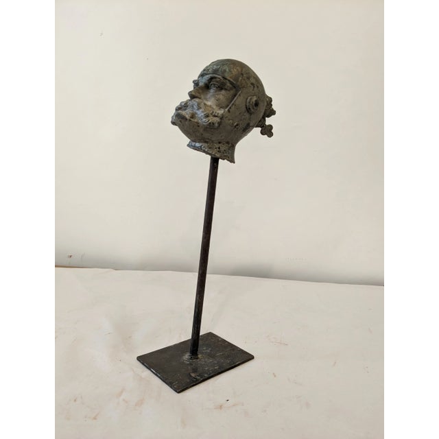 This fragment of a warrior's head is mounted on an iron stand.