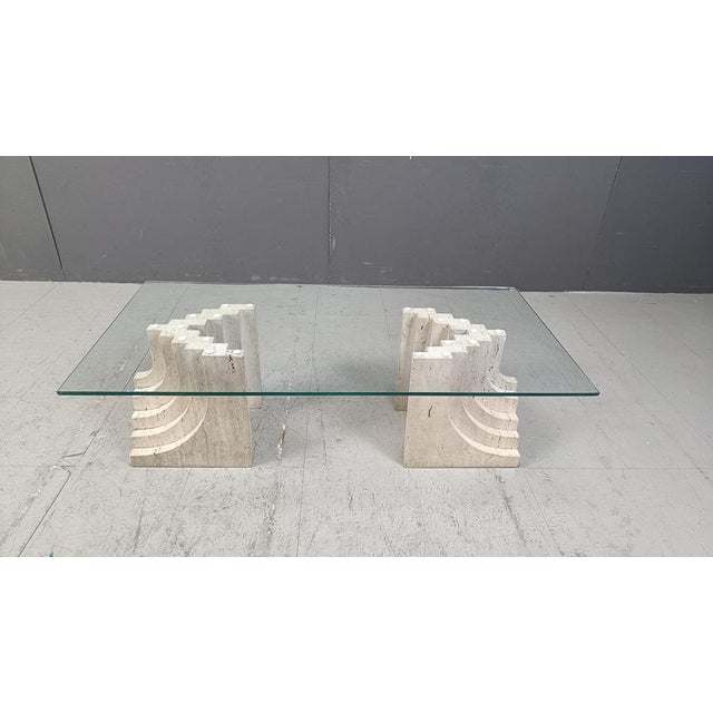 Vintage travertine coffee table with a beveled oval glass top and stepped travertine bases in the style of Carlo Scarpa....