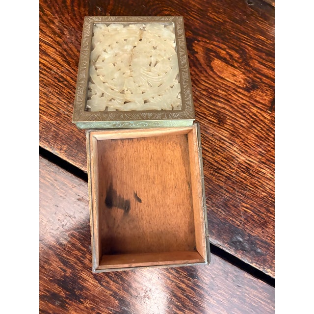Decorative trinket box featuring a carved stone panel set into a brass or brass-tone metal frame, with a fitted wooden...