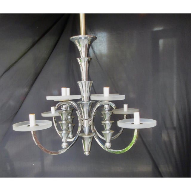 Vintage 8-light chrome chandelier. Shiny chrome surface with opaque flat white shades around each candle stem. Each stem...