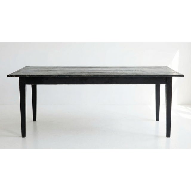 This antique Belgian farmhouse table features a beautifully primitive silhouette and a heavily worn black paint finish....