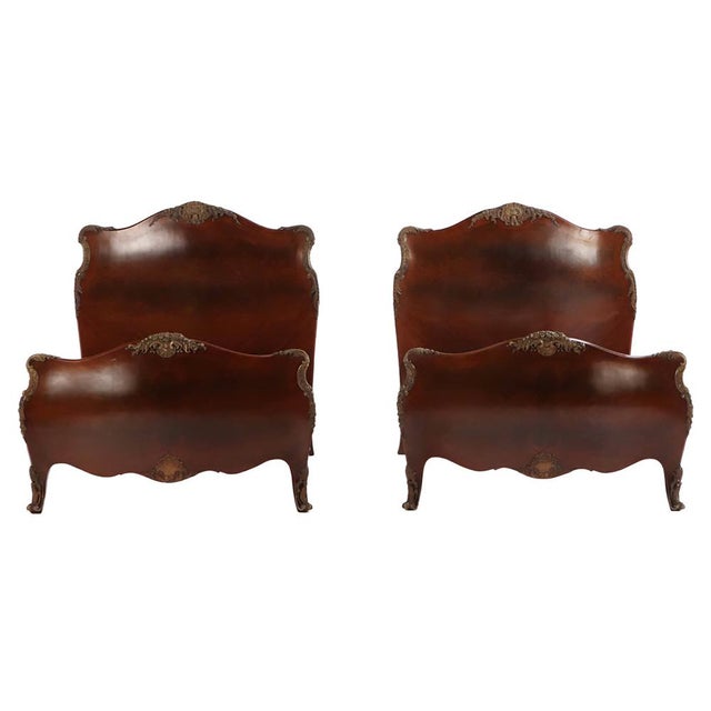 A striking pair of early 20th-century French twin beds showcasing the voluptuous curves of the Louis XV–inspired bombé...