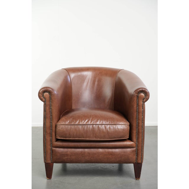 This beautiful cognac-colored English-style cowhide leather club armchair features a comfortable seat, a loose seat...