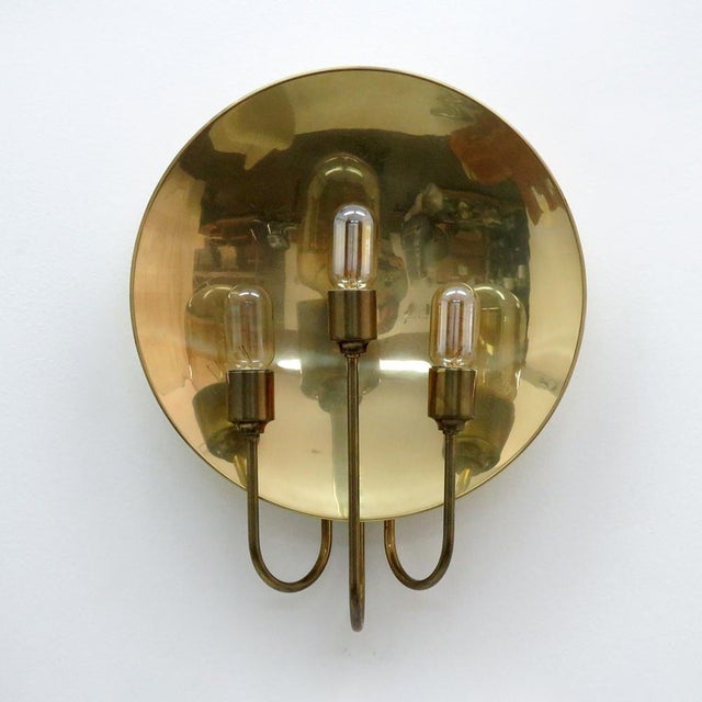 Wonderful 3-arm brass wall light designed by Florian Schulz, Germany, 1960 with three light sources in front of a circular...