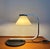 Nice minimalistic vintage design table or desk lamp. Heavy cast iron round shaped base and a metal curvy frame which holds...