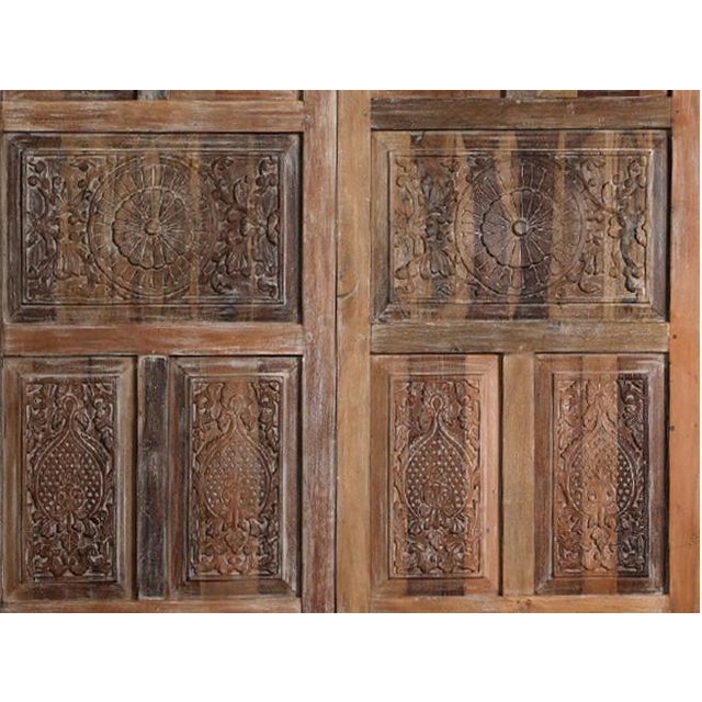 This exquisite antique sliding barn door features intricate hand-carved floral detailing set into richly aged rustic wood....