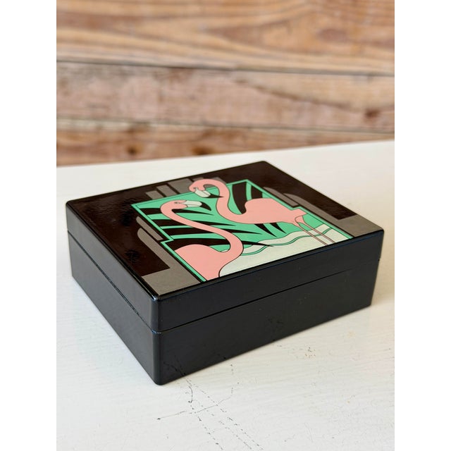 A bold and playful 1980s decorative box featuring a graphic pair of pink flamingos set against a tropical Art...