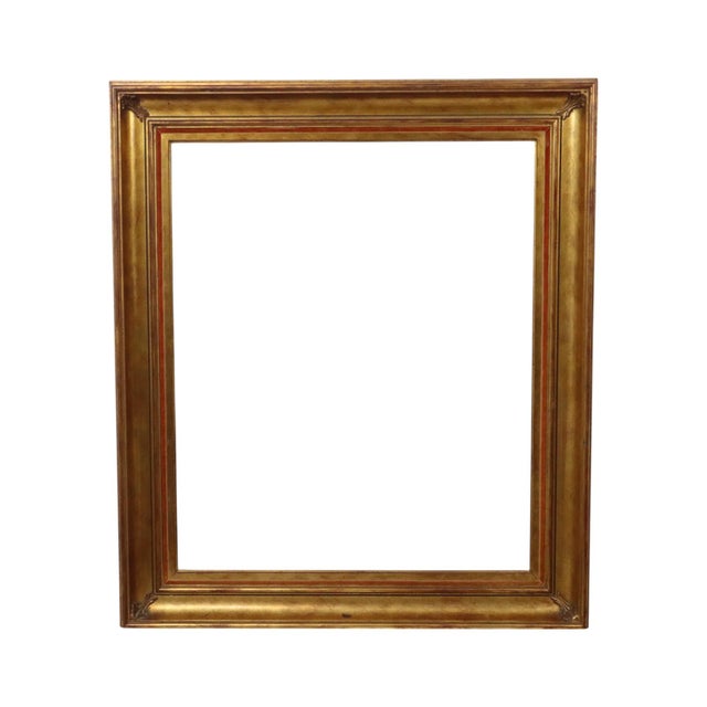 Old gold-colored wooden frame with a beautiful aged patina, entirely in a classic style, decorated all around with a red...