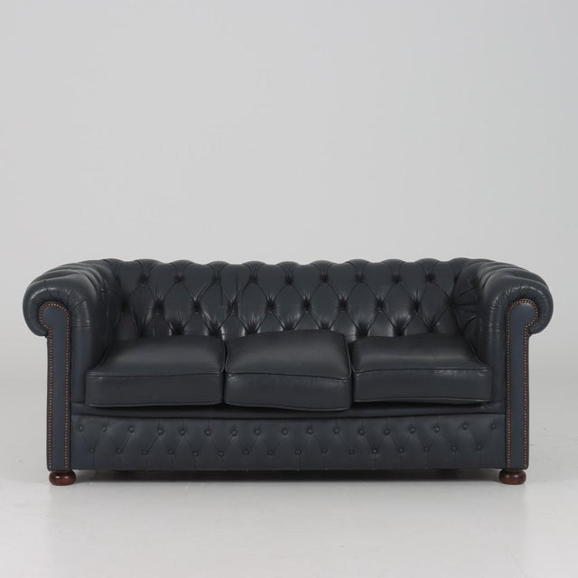 Elegant three-seater Chesterfield sofa from Winchester. The classic and timeless design, crafted in navy blue leather with...