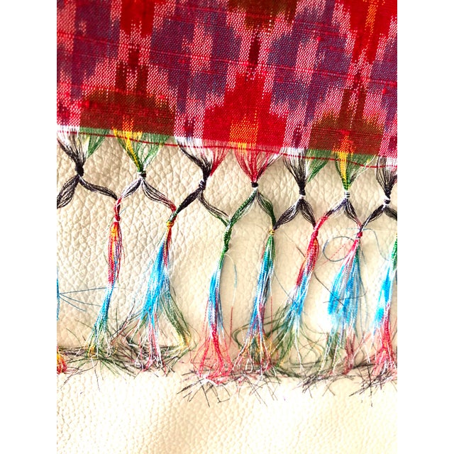 A hand-woven length of raw silk fabric in red with intricately woven diamonds in jewel tones of blue, green, pink, yellow....