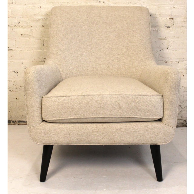 This is a mid-century styled cream lounge chair from Room & Board. The piece is comfortable with a deep sitting seat....