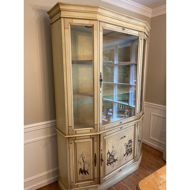 Chinoiserie china cabinet by Jasper cabinet. Features gold detailing on backdrop. Color is a very dark ivory and appears...