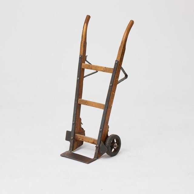 Characterful early 20th-century hand truck crafted from solid wood and iron. The piece features a tall wooden frame...