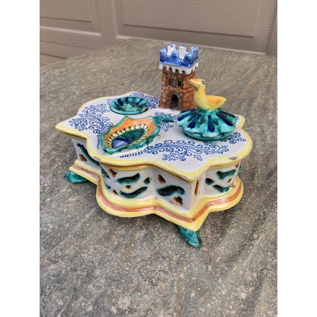 A beautiful hand painted blue, white, yellow, and green Allegorical faience pottery desk stand inkwell featuring a castle,...