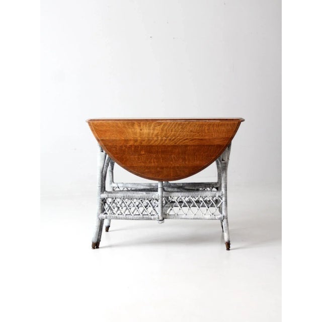 This is a beautiful 19th century wicker gate leg table. The Victorian drop leaf table features a white-washed wicker base...