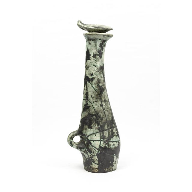 A liqueur decanter with three matching celadon-grey glazed earthenware glasses, decorated with incised black engravings...