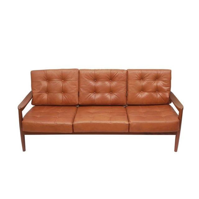 Classic 1960s three-seater sofa in Scandinavian style. Beautifully shaped frame made of dark solid wood. The back is...