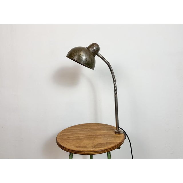 Industrial flexible gooseneck table lamp made in former Czechoslovakia during the 1960s. It features a green metal shade a...