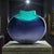 A signed studio-glass vase by Australian artist Maureen Williams, distinguished by a flattened “moon” silhouette and a...