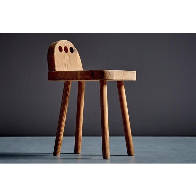 This stool features a solid pine construction with a broad, gently rounded seat and a sculptural backrest with three...