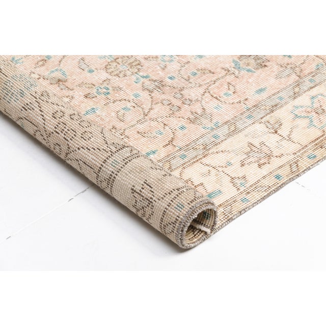 This is a vintage Turkish Oushak rug from the Mid 20th Century. The piece was hand-knotted.