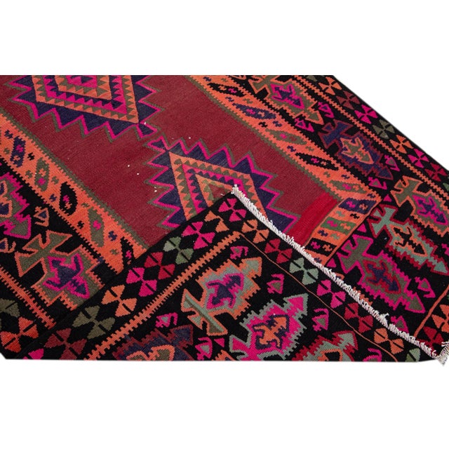 Beautiful kilim handmade wool runner with a red field. This Vintage flatweave rug has pink, black, and brown accents...