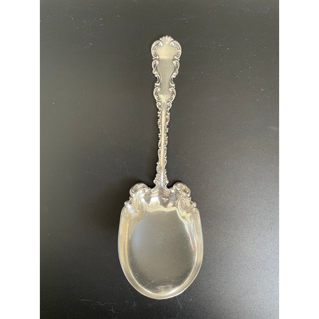 Antique sterling preserve spoon in the Louis XV pattern by Whiting Manufacturing Co. The design features the handle and...