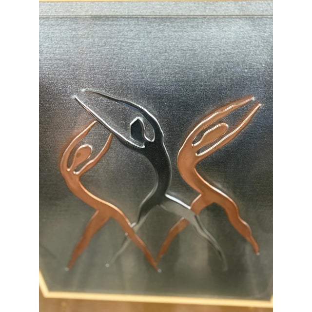 Striking mid-century modern metal wall sculpture depicting three abstract human figures in motion, rendered in sculptural...
